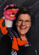 Molly Babcock is seen wearing glasses with a muppet on her shoulder.